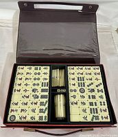 Full set of Mahjong tiles and accessories arranged in brown carrying case.