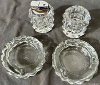 Photo of full smoking set: 2 crystal ashtrays, table lighter, and match holder on dark background.