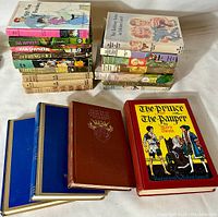 Stack of vintage hard-cover books seen from above on a white background. Includes colorful and illustrated dust jackets. Titles such as The Prince and the Pauper are visible.
