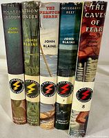 Five Rick Brant Science-Adventure books standing upright, spines showing titles and series numbering, all with original dust jackets.