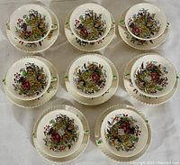 Top-down view of 8 double-handled soup cups on matching saucers, showing floral pattern inside cups and on plates.