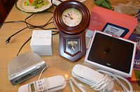 Full view of lot with two clock radios, wooden hanging clock, digital clock, and two white telephones arranged on a table