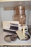 Photo of the Cuisinart DLC-10 Plus food processor along with two stainless steel discs, food pusher, spatula, and instruction manual.