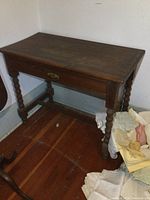 Front and side view of antique solid wood desk showing turned legs, drawer with handle and keyhole.