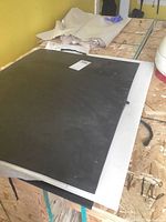 Black portfolio binder lying on workbench with rolled sheets behind