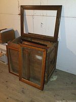 Crate filled with large picture frames, some leaning against the sides and one frame balanced on the edge.