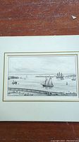 Black and white print depicting a sailing ship and smaller boats on water, mounted on a cream mat with double-lined border.