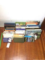 Books arranged on wooden floor with titles clearly visible, showing a collection of sailing and history-themed books.