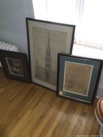 Three framed architectural images leaning against wall