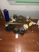 Overall view of lot showing yellow fans, white stoneware piece, brass fixtures, wooden carved piece, metal parts.