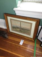 Framed watercolor painting leaning against wall on floor