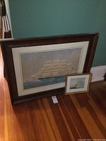Both framed paintings leaning against green wall on hardwood floor