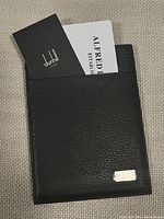 Top view of black leather Alfred Dunhill card holder with certificate partially inserted in the card slot.