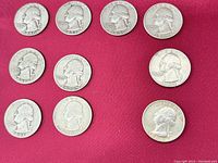 Top-down view of all 10 silver quarters arranged on red fabric. Dates and typical wear visible.