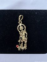 Front view of gold tone St. Lazaro pendant with a small red accent stone on the dog figure.