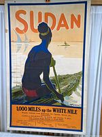 Full view of vintage travel poster showing person on reed boat on White Nile, mounted on poster board rails.