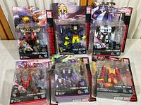 Six Transformers figures in original sealed packaging from the Power of the Primes and Titans Return lines, showing front view of the entire set including Snarl, Decepticon Krok, Jazz, Slug, Blot, and Firedrive & Autobot Hot Rod.