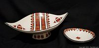 Two decorative ceramic bowls side-by-side: a large footed elongated bowl and a smaller round bowl, both with burnt orange and black Ukrainian folk geometric patterns on white.