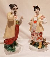 Front view of male and female ceramic figurines depicting characters from the 1939 opera Zaporozhets za Dunayem, showing clothing details and facial features.