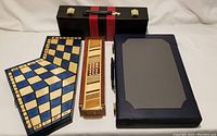 Four game sets with closed cases: Chess for Three tri-fold board, wood dominoes box, Backgammon case, and Rummy case.