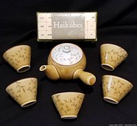 Top view of Japanese tea set including teapot and 5 matching teacups, along with the Haikubes word game box behind them.