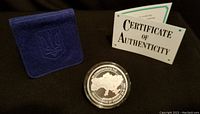 Medallion in hard plastic case with navy blue felt holder and certificate of authenticity in background.