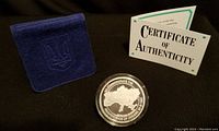 Medallion in plastic capsule with felt holder and certificate displayed on black background