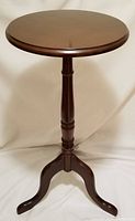 Full front view of the wood accent table showing the round top, central turned pedestal, and three curved legs