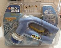 Front view of Black & Decker cordless power scrubber in clear plastic packaging showing blue scrubber with ergonomic handle and multiple cleaning heads.