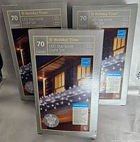 Three boxes of Holiday Time 70 Count LED Star Icicle Light Sets, showing front packaging with energy star badge and light detail image.