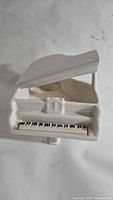 Top-down view of the white ceramic grand piano planter showing piano keys and open lid.
