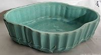 Side view showing the scalloped rim and vertical ridges on the green ceramic planter, glossy glazed finish visible.