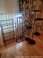 Photo showing all three metal plant stands in a group beside window with wooden floor.