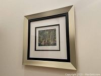 Framed AJ Casson 'Blue Heron' print mounted on a wall showing the silver and black frame.