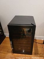 Closed front view of the black bar fridge on hardwood floor