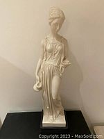 Front view of the Greco Roman maiden statue on black base showing draped clothing and vessel in hand