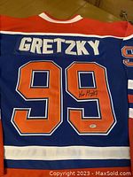 Back of jersey showing 'GRETZKY' nameplate, number 99, with Wayne Gretzky's signature on the lower '9' and authenticity sticker.
