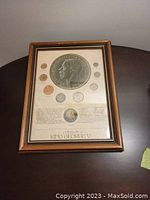 Full frontal photo of one framed King George V coin set with embossing and coins.