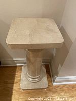 Square marble top piece of the plant stand with beige veining, viewed from an angle.