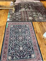 Photo showing both area rugs on wooden floor with the floral geometric patterned rug in brown and the oriental style rug with blue and red in front.