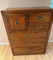 Front view showing the five drawers and one cabinet door with brass recessed handles.