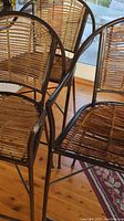 Three metal and wicker bar stools with woven seats and backs viewed from above and side, showing the curved backrests and footrests.