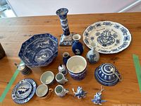 Overview photo showing the full assortment of blue and white English and European ceramics on a table, including plates, vases, jugs, a covered jar, and small figurines.