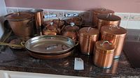 Set of copper kitchen items including pots, pans, canisters, teapots, chafers, and ice buckets on countertop.