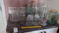 Overview of all glass items on countertop including jars, jugs, vases, and serveware tray
