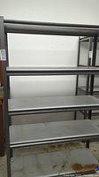 Full view of metal shelving unit showing multiple shelves with surface dirt and rust spots.