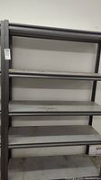 Front view of the gray metal shelving showing five shelves with some dirt and dust accumulation.