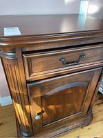 Close-up of wood nightstand showing detailed front with drawer handle, cabinet door with knob, and fluted side paneling.