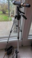 Full view of Bushel telescope mounted on Bell & Howell tripod with attached focusing knob and adjustable tripod legs, showing overall setup.
