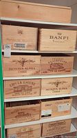 Full view of multiple wooden wine crates stacked on shelving unit showing brands and logos engraved/printed on wood